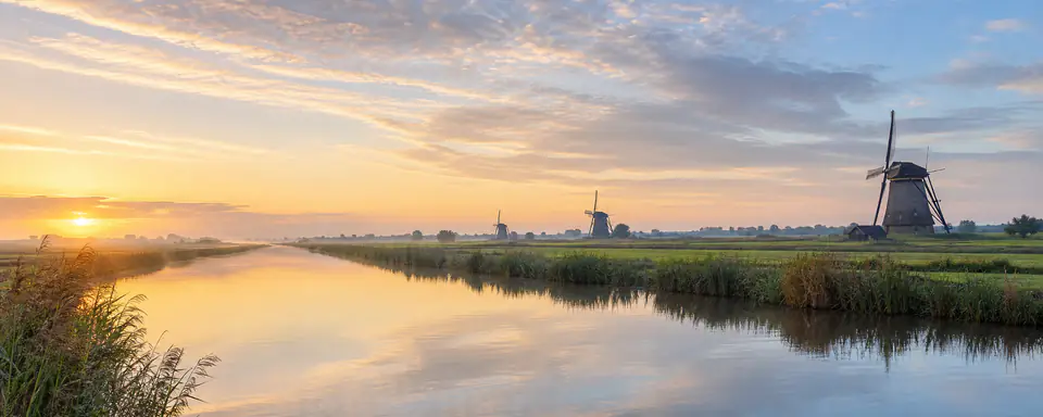 Illustrated Dutch polder landscape with a canal, windmills, and sunset